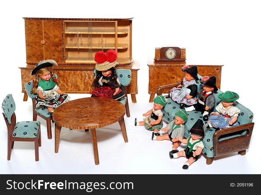 8 dolls in traditional European (I think they are Austrian but not sure) dresses sitting on chairs and couch round a table (old hand made furniture) with racks on the background. 8 dolls in traditional European (I think they are Austrian but not sure) dresses sitting on chairs and couch round a table (old hand made furniture) with racks on the background.