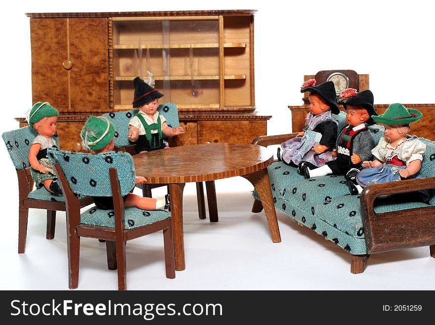 6 dolls in traditional European (I think they are Austrian but not sure) dresses sitting on chairs and couch round a table (old hand made furniture) with racks on the background. 6 dolls in traditional European (I think they are Austrian but not sure) dresses sitting on chairs and couch round a table (old hand made furniture) with racks on the background.