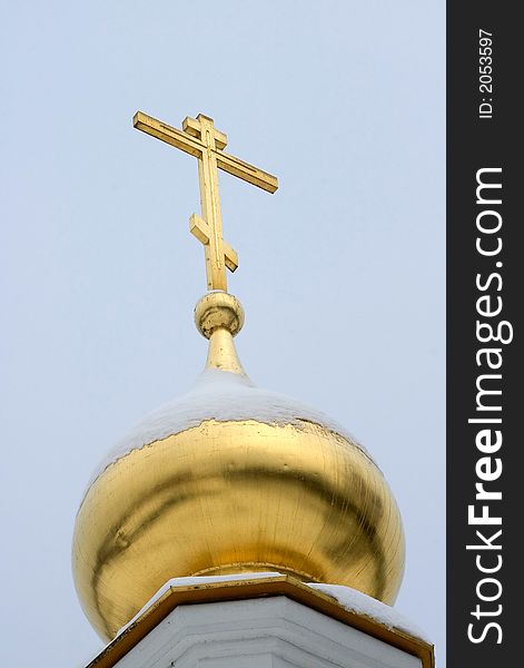 Gold dome of church close up, powdered by a snow, on a background of the monophonic blue sky