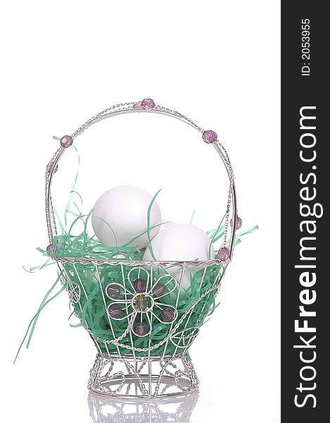 A small, dainty silver Easter basket filled with eggs. White background. A small, dainty silver Easter basket filled with eggs. White background.