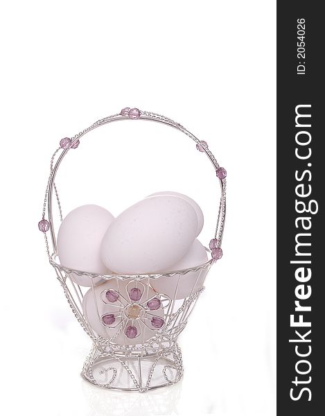 A small, dainty silver Easter basket filled with eggs. White background. A small, dainty silver Easter basket filled with eggs. White background.