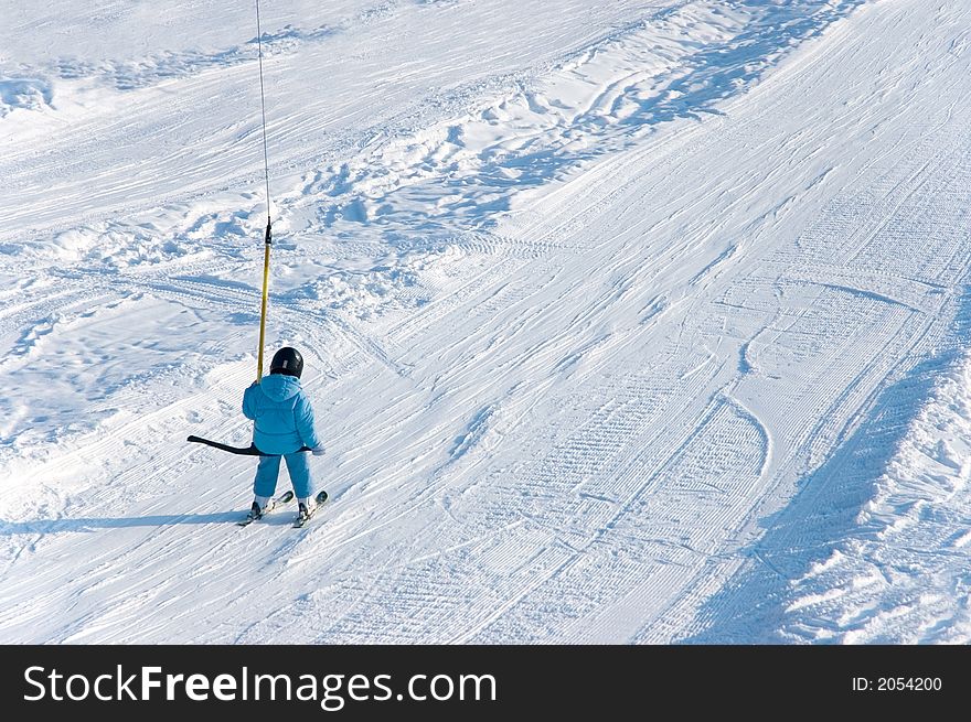 Young downhill skier going up with elevator
