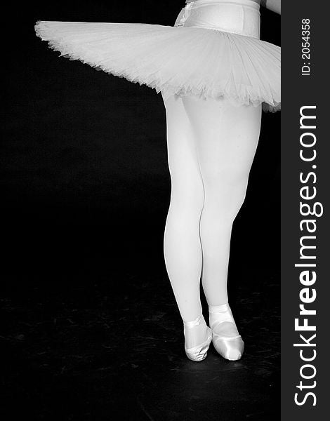 Ballerina standing in a drak black room with a white tutu. Ballerina standing in a drak black room with a white tutu
