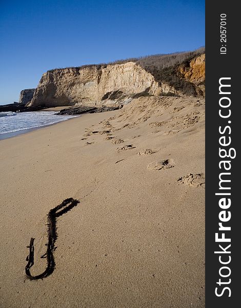 Trail of steps on wet sand of a beach with a remote human figure. Trail of steps on wet sand of a beach with a remote human figure