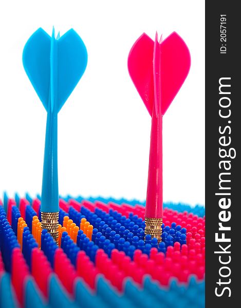 Isolated photo of red and blue toy darts pinned to the target, representing the concept of competition. Isolated photo of red and blue toy darts pinned to the target, representing the concept of competition.