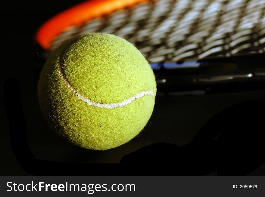 Tennis equipment - ball and racket on black. Soft light, shallow depth of field.