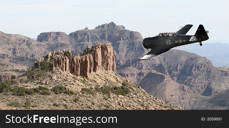 An old military prop plane flies low over a desert landscape in the superstition mountains of Arizona. Taken from on top of the flatiron. An old military prop plane flies low over a desert landscape in the superstition mountains of Arizona. Taken from on top of the flatiron.