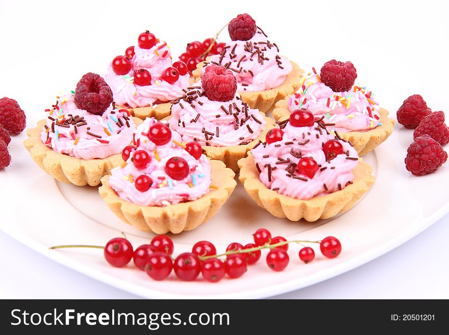Tartlets with whipped cream and fruits - raspberries and redcurrants - on a plate