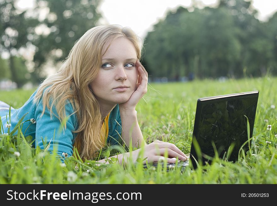 Portrait of pretty woman with laptop on the green grass
