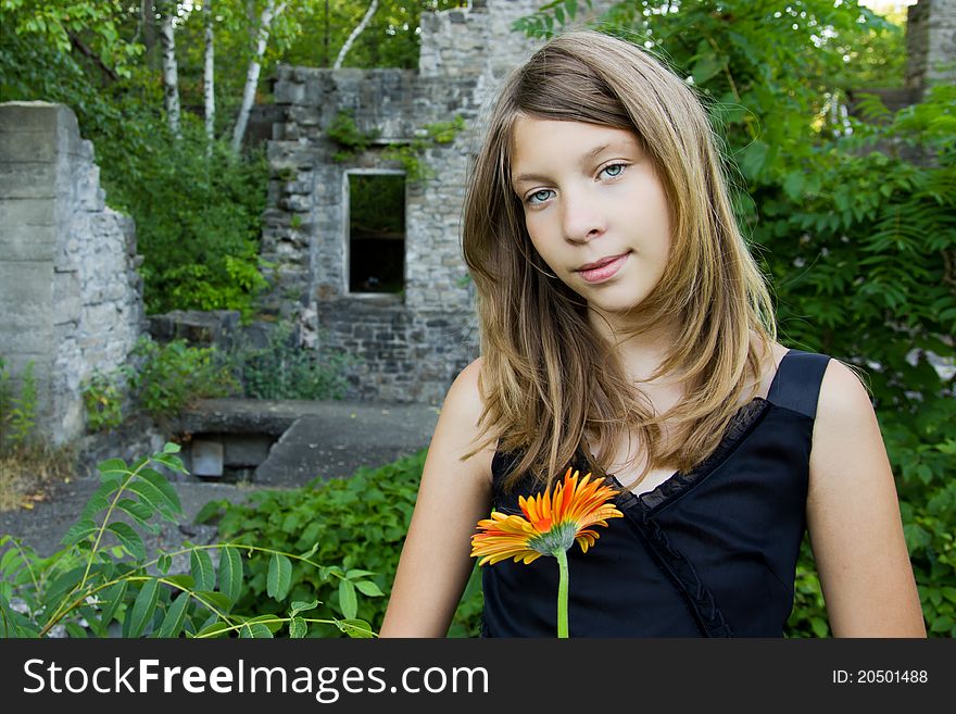 Girl standing in stone ruins holding a flower