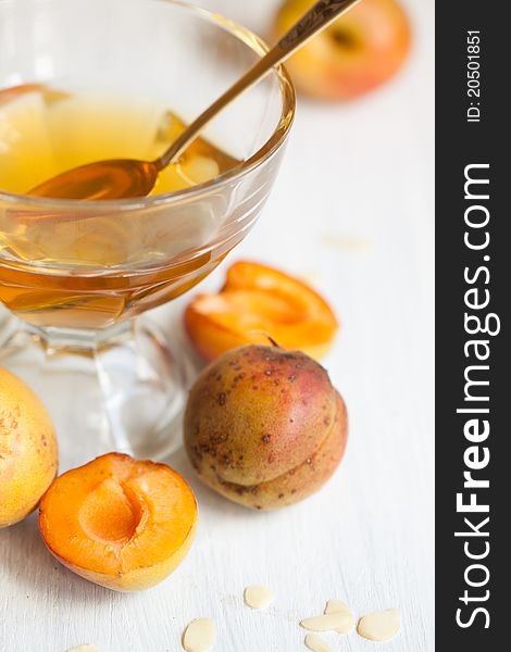 Fresh apricots with cup of honey on white wooden table. Fresh apricots with cup of honey on white wooden table