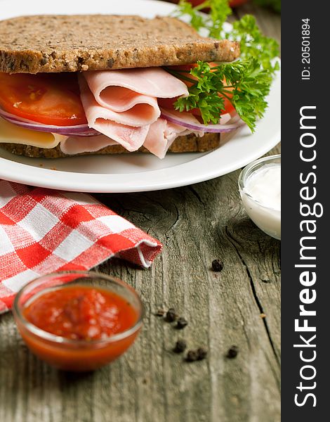 Fresh sandwich with cheese, ham and ketchup on old wooden table. Fresh sandwich with cheese, ham and ketchup on old wooden table