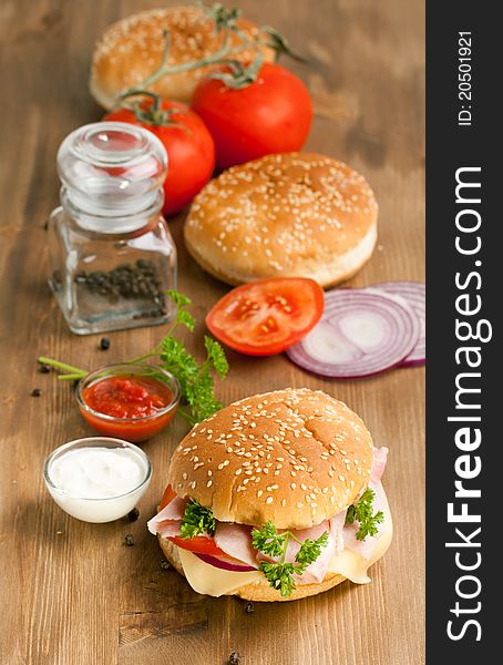 Fresh hamburger with tow kind of sauce and fresh tomatoes on wooden table. Fresh hamburger with tow kind of sauce and fresh tomatoes on wooden table