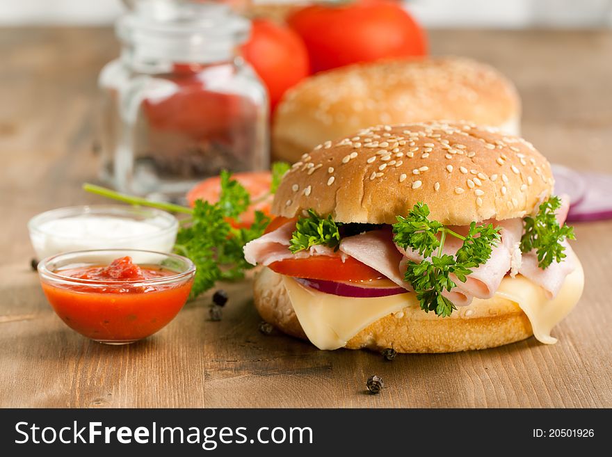 Fresh sandwich with cheese, ham and tomato and tow kind of sauces on wooden table. Fresh sandwich with cheese, ham and tomato and tow kind of sauces on wooden table