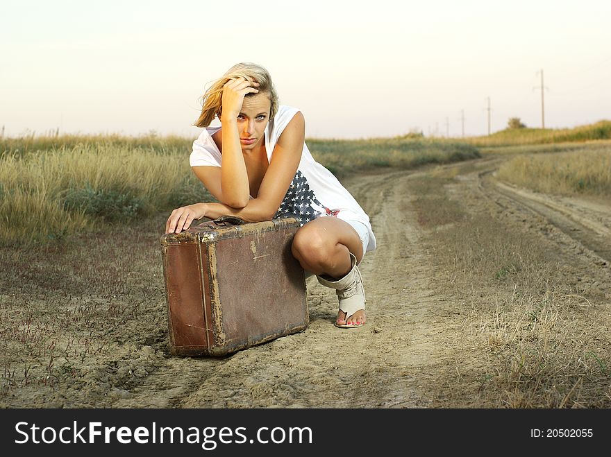 Pretty girl with a suitcase on a countryside road