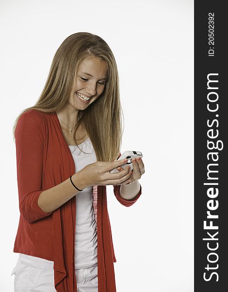 A laughing teenage female girl texting on a cell phone against a white background. A laughing teenage female girl texting on a cell phone against a white background.