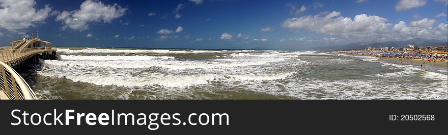 A panoramic landscape whit pier, beach and rough sea.