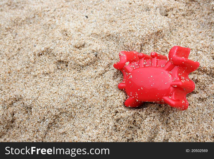 A toy crab on sand. A toy crab on sand