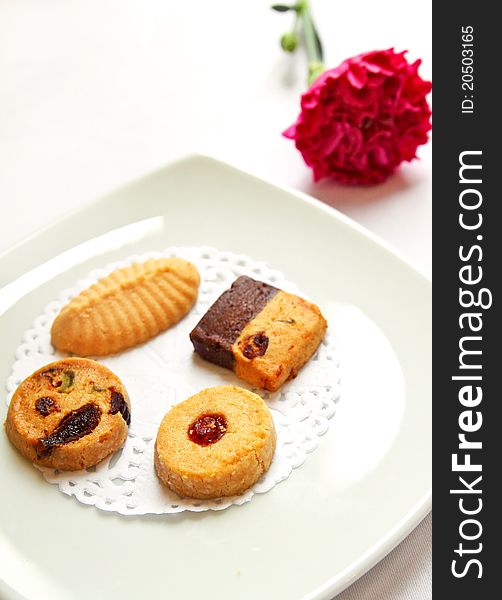 Various cookies on white dish decorated with pink flower