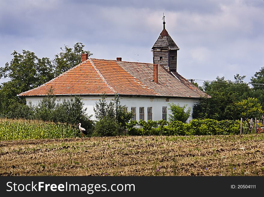 Old abandoned Hungarian church next to a ploughed field with a stork. Old abandoned Hungarian church next to a ploughed field with a stork