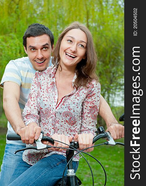 Happy young couple riding bicycle in a park