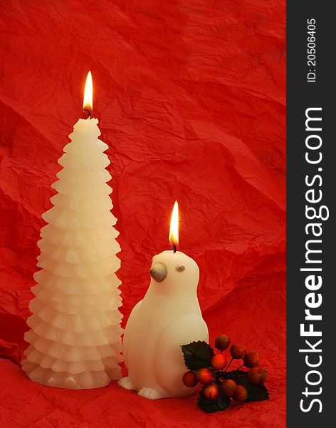 Two white candles with holly barry on red background. Two white candles with holly barry on red background