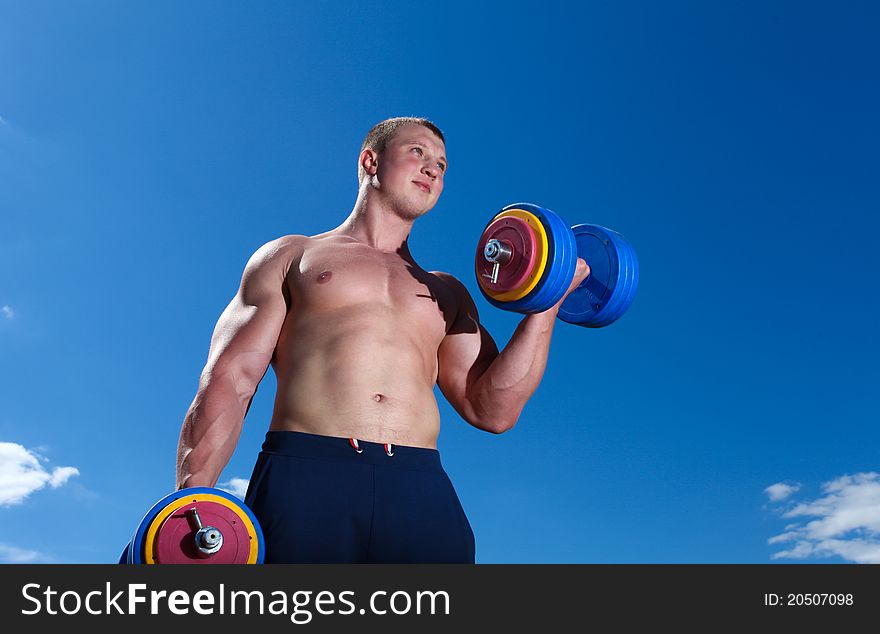 Strong man doing exercises outdoor with dumbbells. Strong man doing exercises outdoor with dumbbells