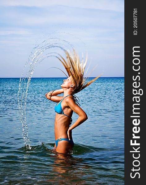 Motion freeze of a blond girl splashing the sea water with her hair. Motion freeze of a blond girl splashing the sea water with her hair