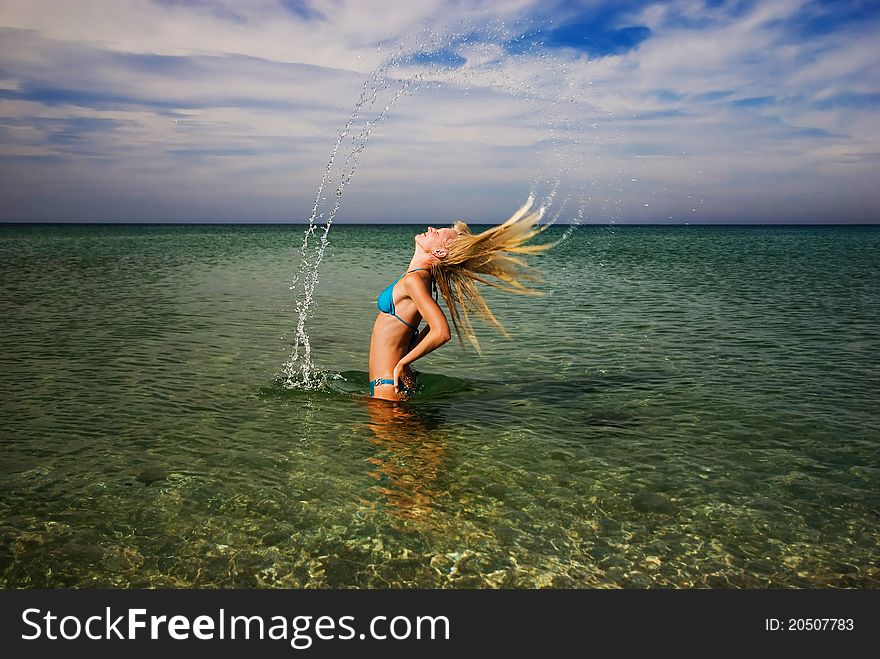 Motion freeze of a blond girl splashing the sea water with her hair. Motion freeze of a blond girl splashing the sea water with her hair