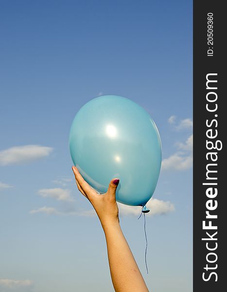 Girl hand holding azure balloon and sky