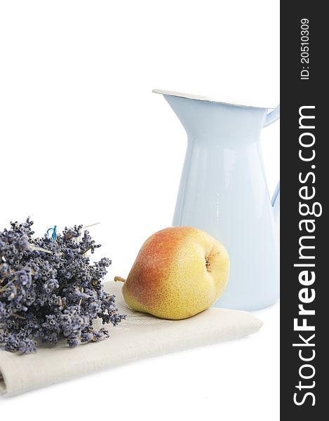 Metallic blue pitcher, pear and a bouquet of dried lavender in the linen napkin on a white background. Metallic blue pitcher, pear and a bouquet of dried lavender in the linen napkin on a white background