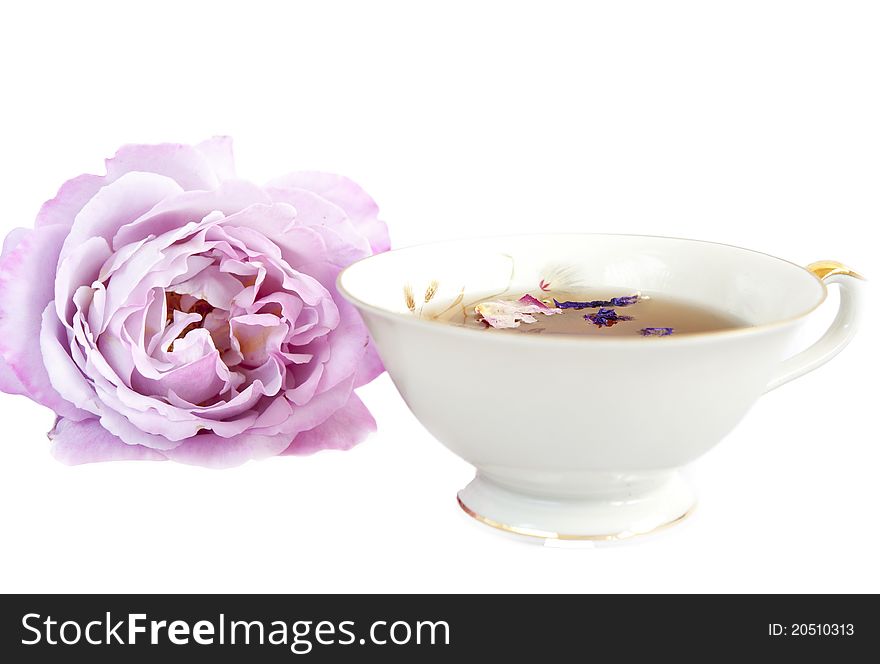Herbal tea in a vintage cup, purple roses on a white background