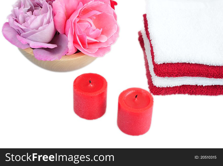 Stack of red and white towels, two red candles, roses in a wooden bowl on a white background. Stack of red and white towels, two red candles, roses in a wooden bowl on a white background