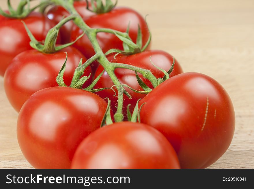 Branch of red tomatoes on a wooden table