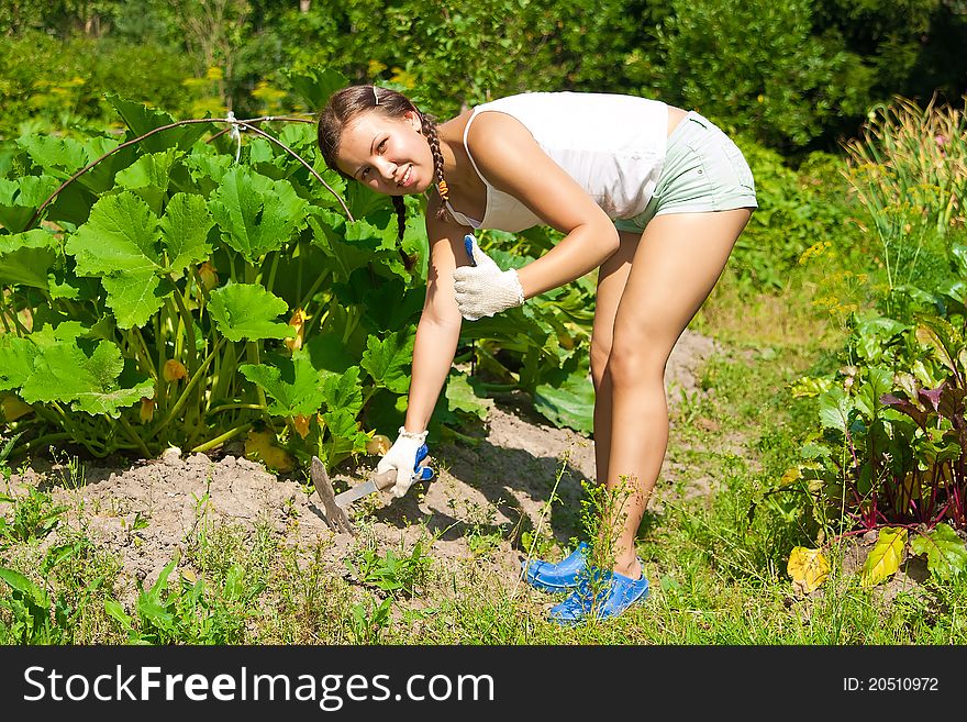 Young woman with hoe working in the garden bed