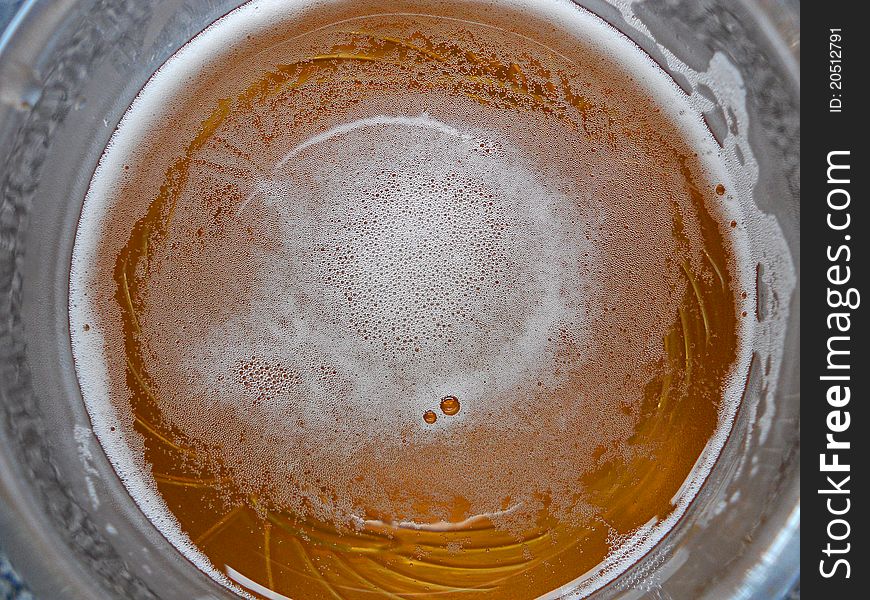 An image of a glass of beer, taken from above, with froth and bubbles