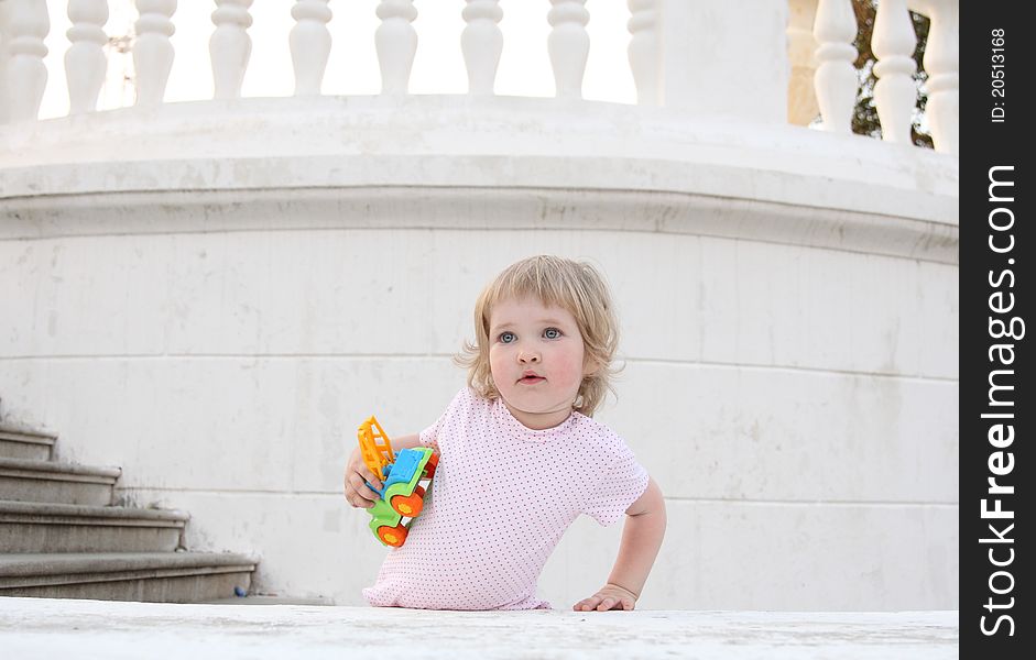 Baby girl with a toy stays on the stairs. Baby girl with a toy stays on the stairs