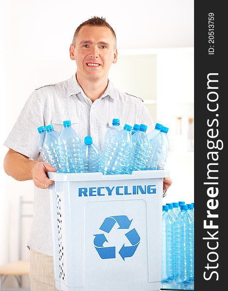 Happy man holding bin full of plastic blue bottles. Happy man holding bin full of plastic blue bottles