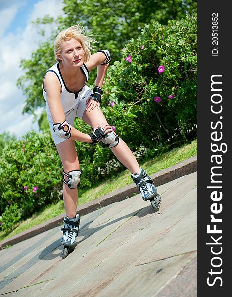 Girl roller-skating in the park at summer