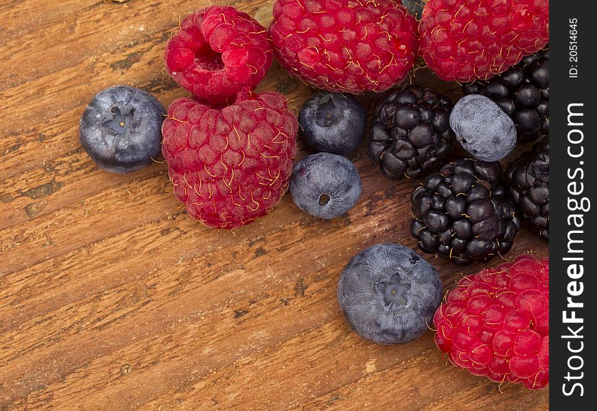 Raspberries, blueberries and blackberries on the wooden background. Raspberries, blueberries and blackberries on the wooden background