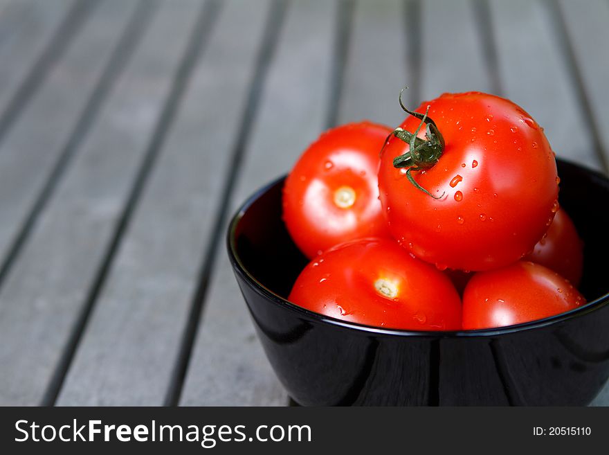 Red tomatoes in black bowl