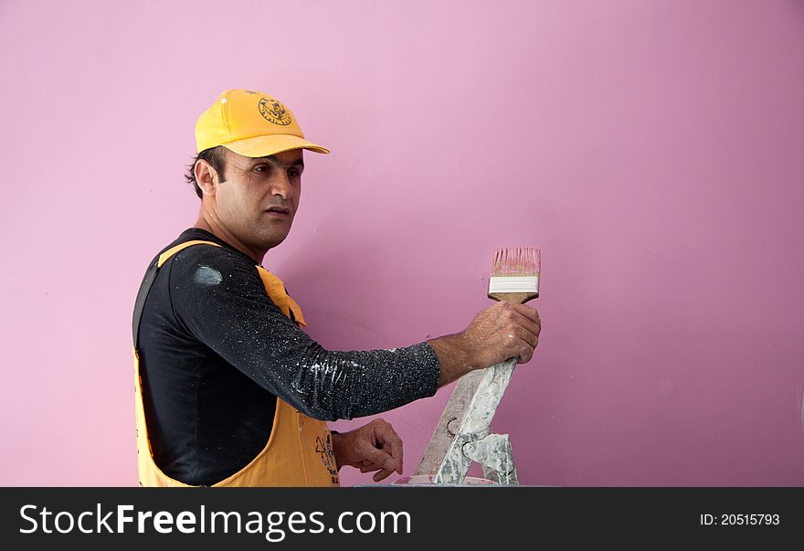 A man painting a wall pink. A man painting a wall pink