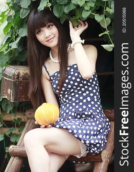 Young Chinese girl holding a melon smiling outdoor in summer. Young Chinese girl holding a melon smiling outdoor in summer.