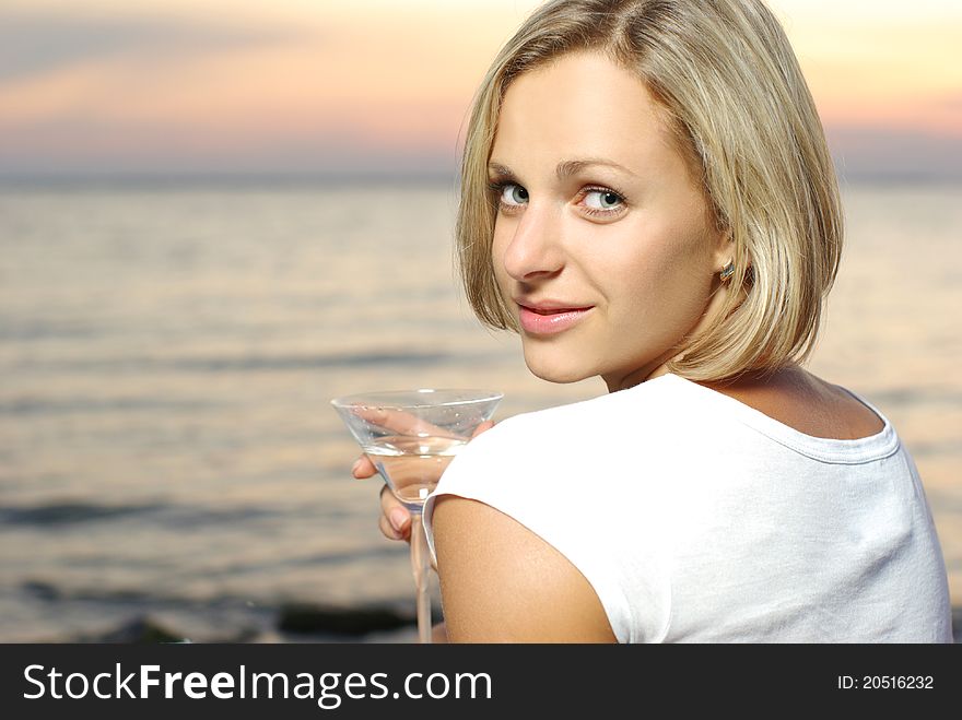 Portrait of a beautiful woman with cocktail on the sunset backgraund