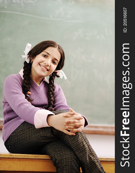 Cute schoolgirl siting on desk