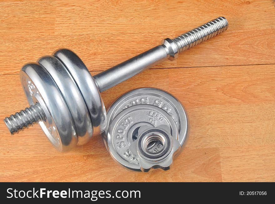 A set of gym weights and bar bell sitting on a wooden
floor