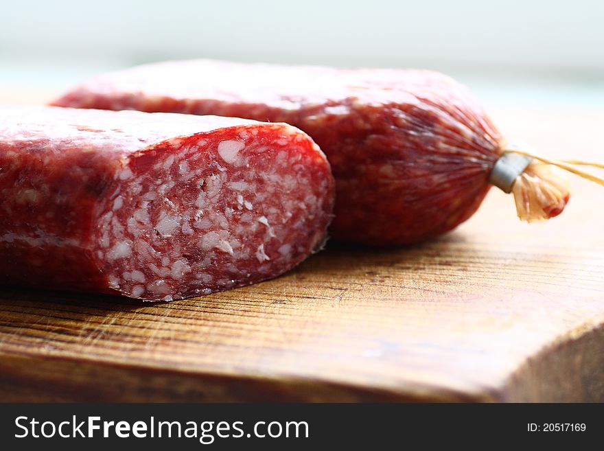 Two halves of Italian smoked sausage salami on wooden cutting board. Two halves of Italian smoked sausage salami on wooden cutting board