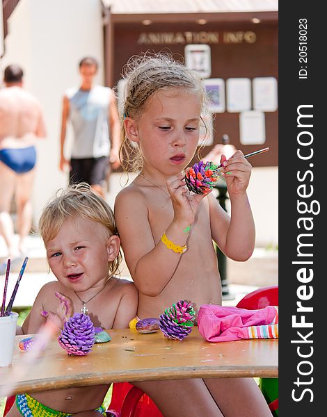 Beautiful girls painting beach pebbles and pine cones outdoor