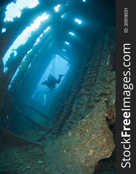 Scuba diver exploring the interior of a large shipwreck. Scuba diver exploring the interior of a large shipwreck