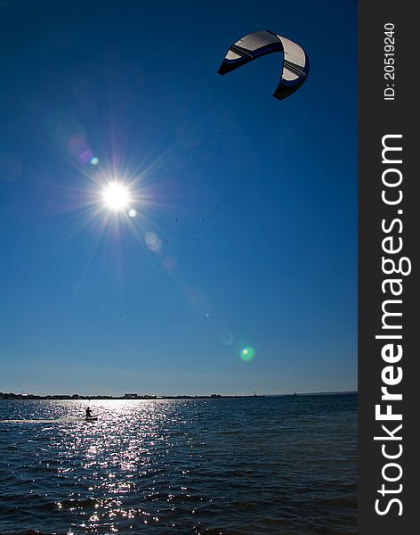 Kitesurfer on the sea against the sun and blue sky